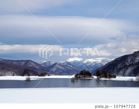 雪解けの始まった福島県、秋元湖。白い雪原と青い湖面、遠方に冠雪の箕輪山が印象的で綺麗だ。 107947728