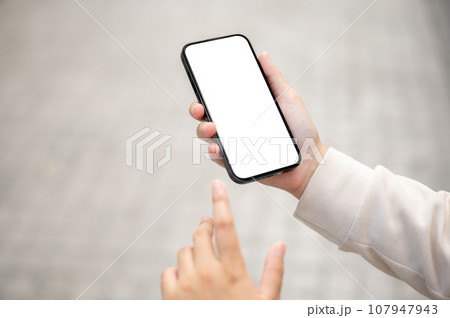 Close-up image of a woman using her smartphone while walking down the street. 107947943