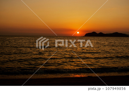 秋の海の水平線に沈みかけた夕日 秋の海の水平線に沈みかけた夕日 107949856
