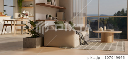 A modern apartment living room with kitchen on the back, a couch and a coffee table on a carpet. 107949966