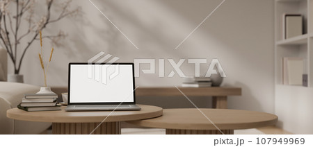 A white-screen laptop mockup on a minimal wood coffee table in a cosy Scandinavian living room. 107949969