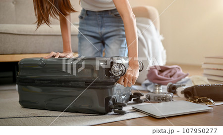 Close-up image of an Asian woman packing her suitcase in her living room 107950277