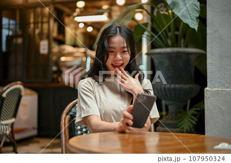 An excited Asian woman is looking at her smartphone screen with a surprising face 107950324