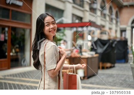 An attractive Asian female enjoying her shopping day in the city market on the weekend. 107950338