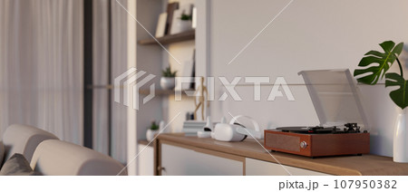 A vintage vinyl record player on a wooden shelf in a cozy Scandinavian living room. 107950382