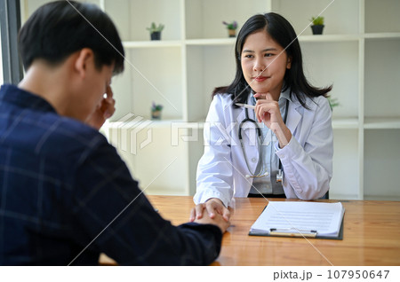 A doctor is touching a patient's hand to provide comfort and reassurance during the medical checkup A doctor is touching a patient's hand to provide comfort and reassurance during the medical checkup 107950647