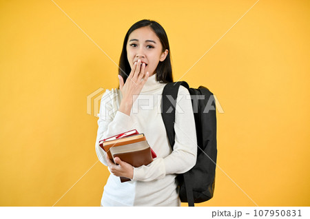 A shocked and excited Asian female college student is covering her mouth, showing a surprise face A shocked and excited Asian female college student is covering her mouth, showing a surprise face 107950831