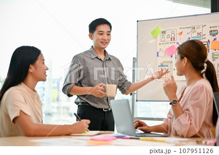 A professional Asian male tech developer is presenting his project to his colleagues in the meeting. 107951126