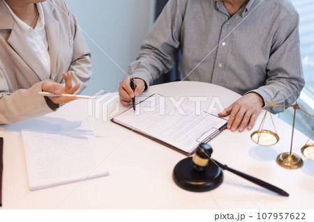 Businesswoman explain data and ask about contract while senior lawyer pointing on contract for sign Businesswoman explain data and ask about contract while senior lawyer pointing on contract for sign 107957622