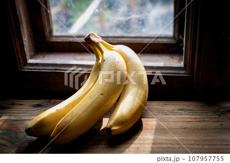 Bananas on the windowsill of an old country house by a wooden window 107957755
