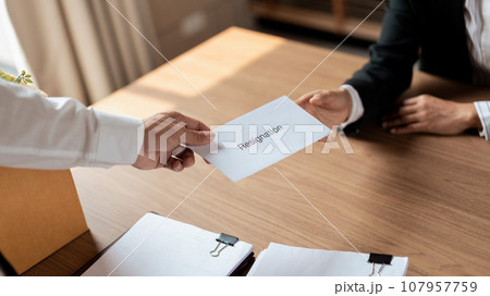 Male employee with belongings cardboard box sending resignation letter to executive for leaving job Male employee with belongings cardboard box sending resignation letter to executive for leaving job 107957759