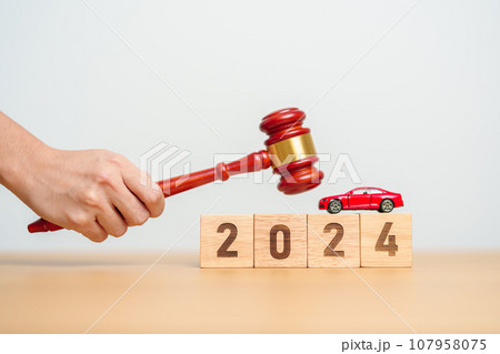 Car Law, Insurance, auto Tax, Auction and Bidding concepts. 2024 year block with crashed small toy car models with Judges gavel on desk in courthouse. 107958075