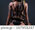 Photo of the sitting woman with crawling yellow anaconda on back 107958287