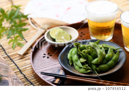 お盆にのせた枝豆とビール 酒の肴に（ お酒のおつまみイメージ ）えだまめの塩茹で 豆 枝まめ すだれ 107958512