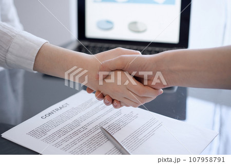 Business people shaking hands above contract papers just signed on the grey table, close up. Lawyers or entrepreneurs at meeting. Teamwork, partnership, success concept Business people shaking hands above contract papers just signed on the grey table, close up. Lawyers or entrepreneurs at meeting. Teamwork, partnership, success concept 107958791