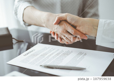 Business people signing contract papers while sitting at the glass table in office, closeup. Partners or lawyers working together at meeting. Teamwork, partnership, success concept Business people signing contract papers while sitting at the glass table in office, closeup. Partners or lawyers working together at meeting. Teamwork, partnership, success concept 107959638