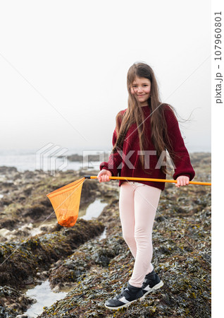 Girl with dark long hair rock pooling at Hope Gap Beach between Seaford and Eastbourne, East Sussex. Beach and sea in foggy morning Girl with dark long hair rock pooling at Hope Gap Beach between Seaford and Eastbourne, East Sussex. Beach and sea in foggy morning 107960801
