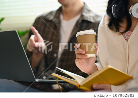 University students using laptop for researching online, collaborating on a project in campus University students using laptop for researching online, collaborating on a project in campus 107962982