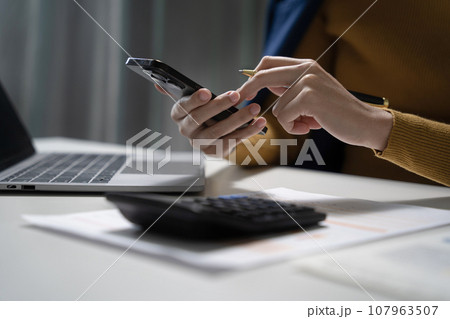 Business women calculate and analyzing graph document financial with laptop  in office. 107963507