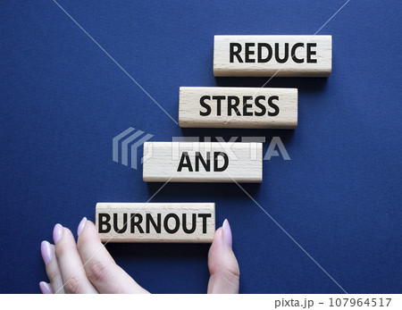 Reduce Stress and Burnout symbol. Concept word Reduce Stress and Burnout on wooden blocks. Beautiful deep blue background. Businessman hand. Business and Reduce Stress and Burnout concept. Copy space 107964517