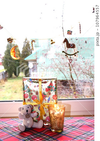 teddy bear with a Christmas gift and a candle in a golden glass candlestick teddy bear with a Christmas gift and a candle in a golden glass candlestick 107964557