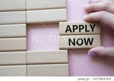 Apply now symbol. Concept word Apply now on wooden blocks. Businessman hand. Beautiful pink background. Business and Apply now concept. Copy space 107964569