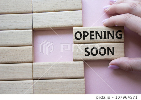 Opening soon symbol. Concept word Opening soon on wooden blocks. Businessman hand. Beautiful pink background. Business and Opening soon concept. Copy space 107964571