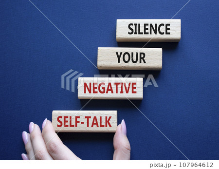 Silence your negative self-talk symbol. Concept words Silence your negative self-talk on wooden blocks. Doctor hand. Beautiful deep blue background. Psychology concept. Copy space. 107964612