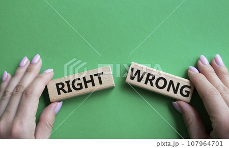 Right or Wrong symbol. Concept word Right or Wrong on wooden blocks. Businessman hand. Beautiful green background. Business and Right or Wrong concept. Copy space Right or Wrong symbol. Concept word Right or Wrong on wooden blocks. Businessman hand. Beautiful green background. Business and Right or Wrong concept. Copy space 107964701