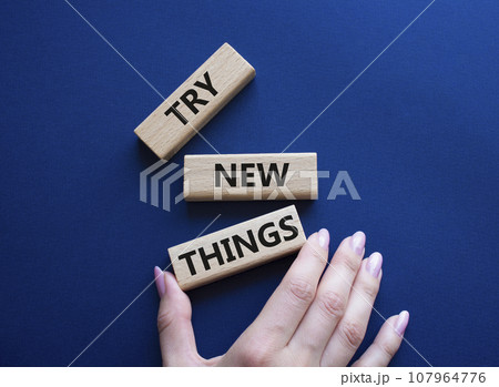 Try new Things symbol. Concept words Try new Things on wooden blocks. Businessman hand. Beautiful deep blue background. Business and Try new Things concept. Copy space. Try new Things symbol. Concept words Try new Things on wooden blocks. Businessman hand. Beautiful deep blue background. Business and Try new Things concept. Copy space. 107964776