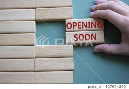 Opening soon symbol. Concept word Opening soon on wooden blocks. Businessman hand. Beautiful grey green background. Business and Opening soon concept. Copy space 107964840