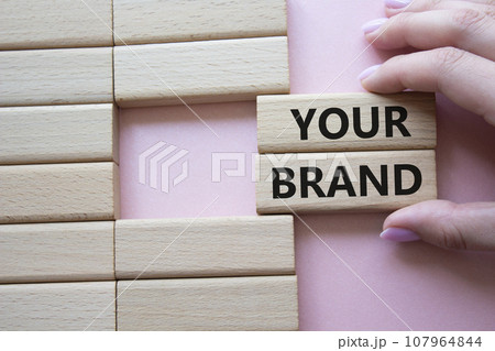 Your Brand symbol. Concept word Your Brand on wooden blocks. Businessman hand. Beautiful pink background. Business and Your Brand concept. Copy space Your Brand symbol. Concept word Your Brand on wooden blocks. Businessman hand. Beautiful pink background. Business and Your Brand concept. Copy space 107964844