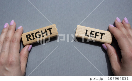 Right or Left symbol. Concept word Right or Left on wooden blocks. Businessman hand. Beautiful grey background. Business and Right or Left concept. Copy space Right or Left symbol. Concept word Right or Left on wooden blocks. Businessman hand. Beautiful grey background. Business and Right or Left concept. Copy space 107964851