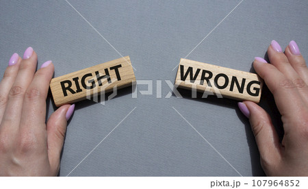 Right or Wrong symbol. Concept word Right or Wrong on wooden blocks. Businessman hand. Beautiful grey background. Business and Right or Wrong concept. Copy space Right or Wrong symbol. Concept word Right or Wrong on wooden blocks. Businessman hand. Beautiful grey background. Business and Right or Wrong concept. Copy space 107964852