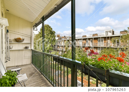 a balcony with flowers and plants on the railings, as seen from an apartment window looking out onto the street a balcony with flowers and plants on the railings, as seen from an apartment window looking out onto the street 107965263