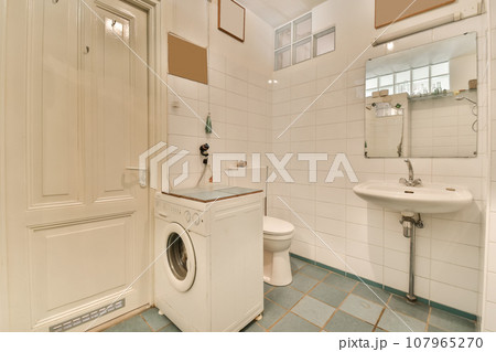 a laundry room with a washer, toilet and sink in the photo is taken from the front door to the bathroom a laundry room with a washer, toilet and sink in the photo is taken from the front door to the bathroom 107965270