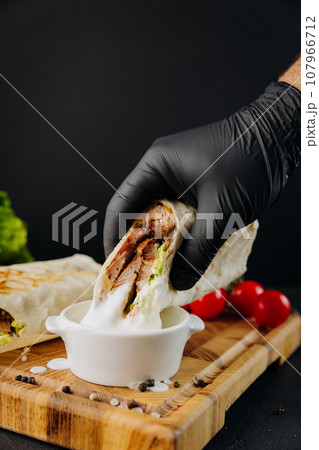 Human hand dips tasty beef shawarma in white sauce tartor. Traditional arab mid east food 107966712