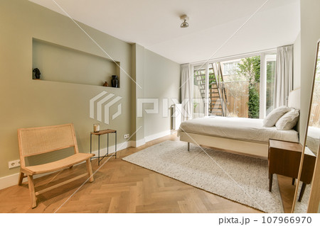 a bedroom with a bed, chair and tv on the wall in it's corner next to a window a bedroom with a bed, chair and tv on the wall in it's corner next to a window 107966970