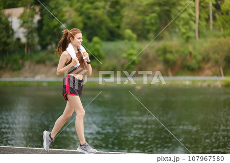 Healthy Asian woman is jogging running outdoor. Sport girl running. Female exercising at outdoor park. Sunset or Sunrise. Healthy Asian woman is jogging running outdoor. Sport girl running. Female exercising at outdoor park. Sunset or Sunrise. 107967580