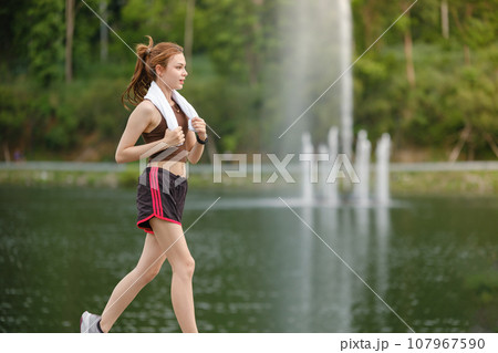 Healthy Asian woman is jogging running outdoor. Sport girl running. Female exercising at outdoor park. Sunset or Sunrise. 107967590