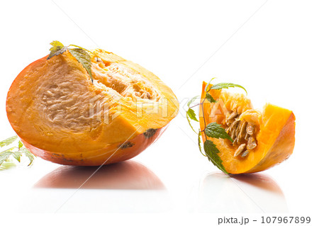 A piece of ripe orange pumpkin with seeds on a white background. 107967899