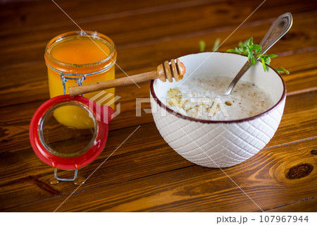 milk oatmeal porridge with honey for breakfast in a bowl wooden table. 107967944