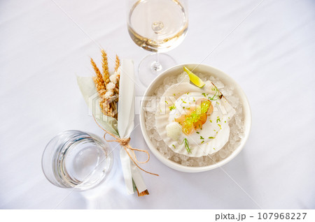 Scallop in sauce with flying fish caviar on a shell on ice in a restaurant 107968227