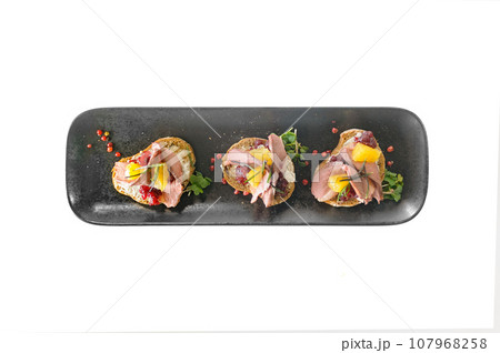 Bruschetta with duck, cowberry jam and orange on black ciabatta toast isolated 107968258