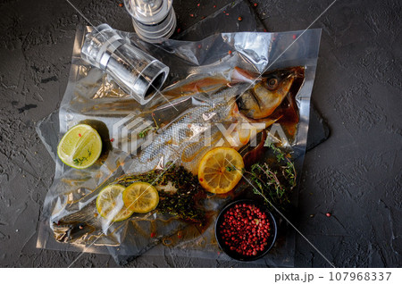 Raw sea bass fish with spices and herbs ingredients on black background 107968337