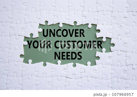 Customer Needs symbol. White puzzle with words Uncover your Customer Needs. Beautiful grey green background. Business concept. Copy space. 107968957