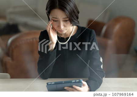 タブレットを見て故人を思い出す女性 107969164