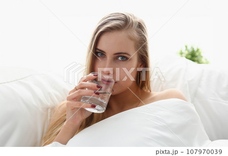 blond woman hold glass of water in arm early morning stay in bed blond woman hold glass of water in arm early morning stay in bed 107970039
