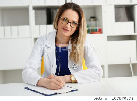 Beautiful smiling female doctor sit at workplace 107970372