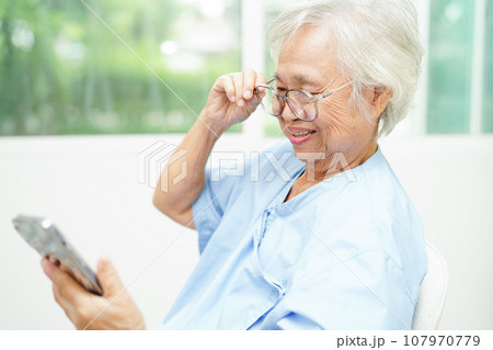Asian senior woman wearing eyeglasses or vision glasses using a smartphone at home care service. Asian senior woman wearing eyeglasses or vision glasses using a smartphone at home care service. 107970779